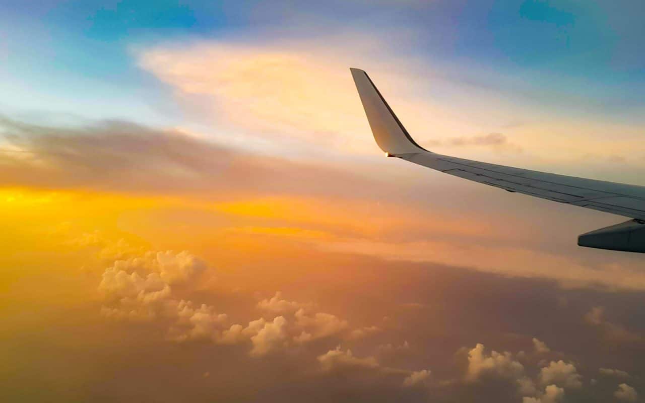 white airplane wing under white clouds during daytime